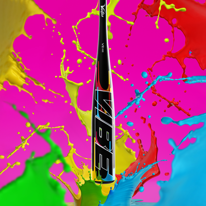 The 2024 Victus Vibe (-5) 2 3/4” USSSA Baseball Bat by Victus stands upright against a vibrant pink background, its black one-piece design featuring bold, colorful “VIBE” lettering and surrounded by splashes of yellow, green, red, and blue paint.