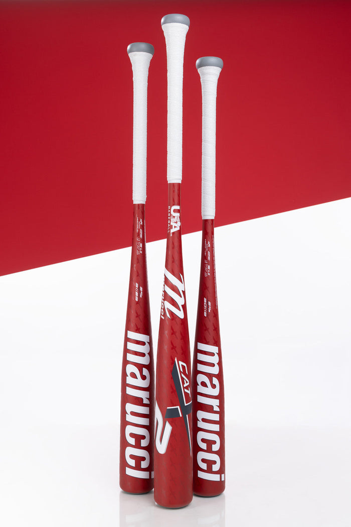 Three Marucci 2025 CATX2 (-11) USA Baseball Bats stand upright, displaying a metallic red finish, bold white branding, and advanced Anti-Vibration Technology against a white and red geometric background.
