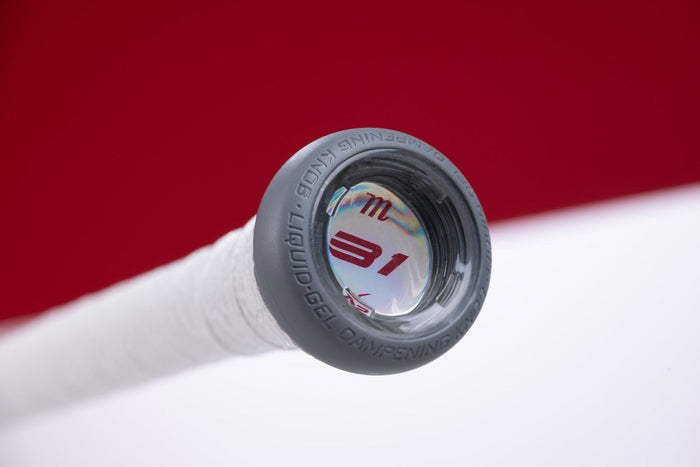 Close-up of a Marucci CATX2 (-11) 2 5/8" USA Baseball Bat (MSBCX211USA) end cap with gray rim and white grip. The cap shows “31” and features Anti-Vibration Technology, set against a blurred red and white background.