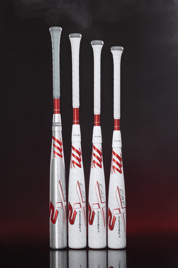 Four Marucci CATX2 Connect (-10) USSSA baseball bats with white handles, red accents, and "M" logos stand upright on a dark, reflective surface with a hint of smoke above them, highlighting their advanced anti-vibration technology.