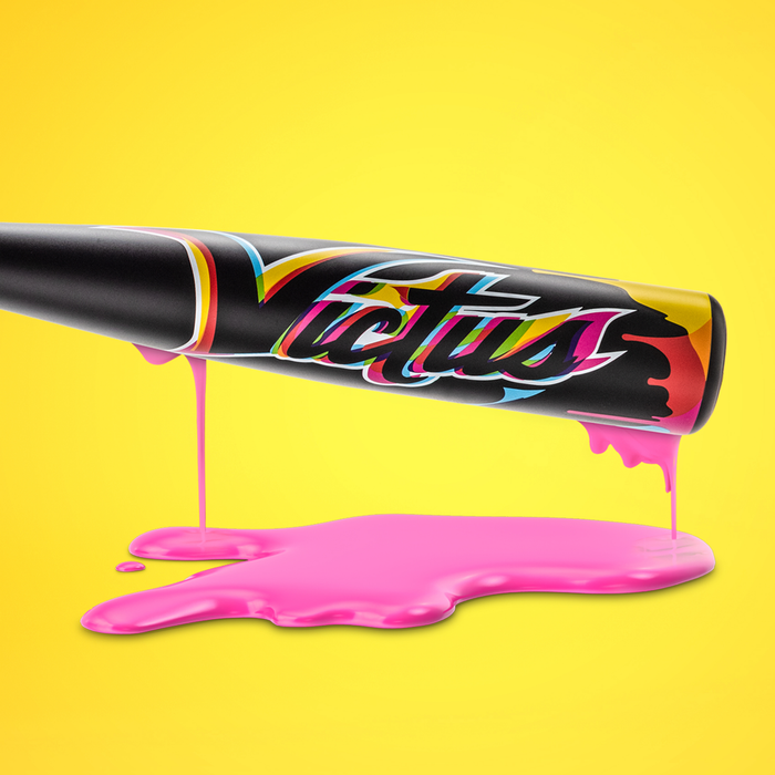 The 2025 Victus Vibe (-3) BBCOR Baseball Bat by Victus, a vibrant one-piece aluminum bat, drips bright pink paint onto a glossy yellow surface, creating an artistic splash against a vivid yellow background.