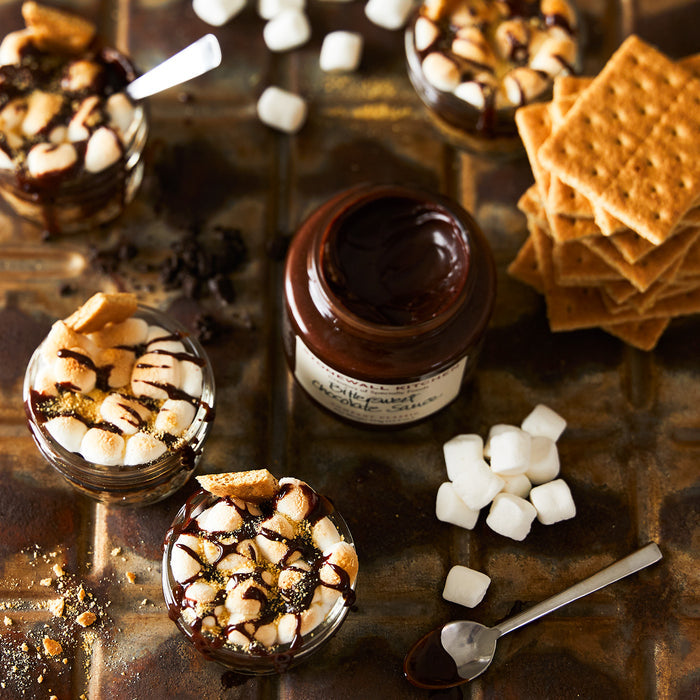 open jar of bittersweet chocolate sauce with marshmallows and graham crackers s'mores in mason jars