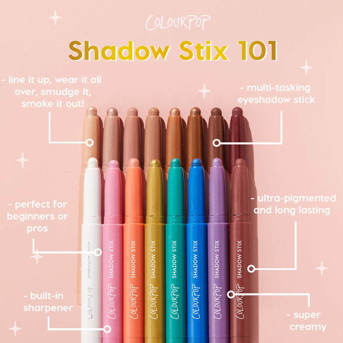 Colourpop Midnight Hour Shadow Stix eyeshadow pencil shown among a rainbow lineup of creamy Colourpop Shadow Stix on a pink background, highlighting its ultra‑pigmented, long‑lasting, multi‑tasking formula for easy eyeshadow looks.