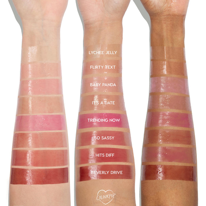 ColourPop So Juicy Plumping Glossy Lip Oil shade Trending Now swatched on three arms in light, medium, and deep skin tones, showing a vibrant rosy pink, high-shine finish and plumping gloss texture alongside other labeled shades for comparison.